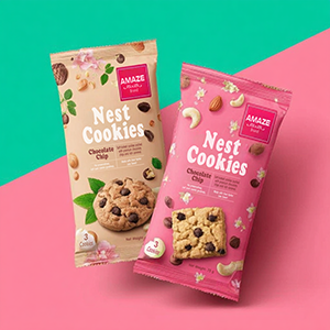 Two chocolate chip cookie pouches (Nest Cookies) on a diagonal split teal and pink background.